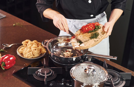 Using equipment. Professional young chef cook in uniform working on the kitchen with vegetables