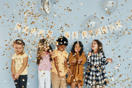 Balloons and confetti. Children on celebrating birthday party indoors have fun togetherの写真素材