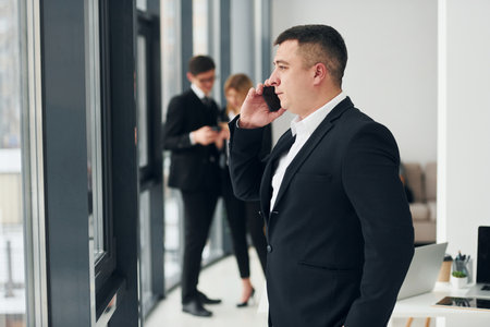 Man holds phone. Group of people in official formal clothes that is indoors in the officeの写真素材