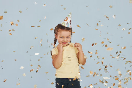 Happy little girl standing and have fun indoors at birthday partyの写真素材