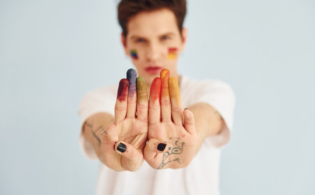 Young gay man is standing in the studio and posing for a camera. Shows gesturesの写真素材