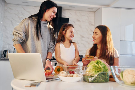 On the kitchen. Female lesbian couple with little daughter spending time together at homeの写真素材