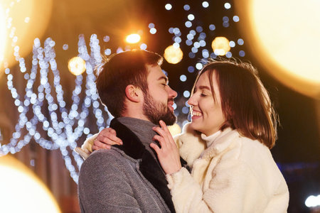 Embracing each other. Happy young couple celebrating New year outdoors on the streetの写真素材