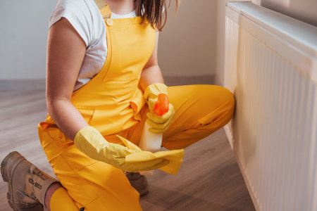 Housewife in yellow uniform works with window and surface cleaner indoors. House renovation conceptionの写真素材