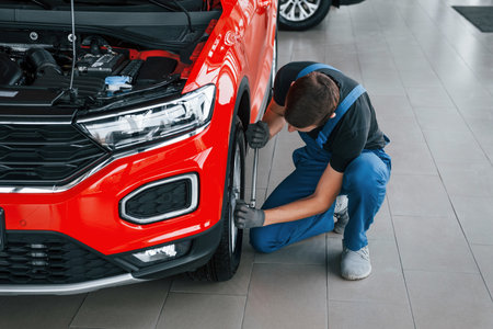 Man in uniform changing tire of automobile. Conception of car serviceの写真素材