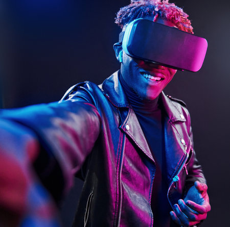 Virtual reality experience. Futuristic neon lighting. Young african american man in the studioの写真素材