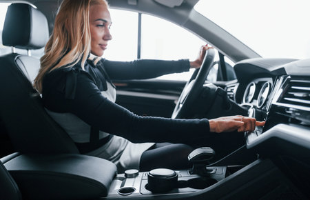 Side view of beautiful blonde in elegant clothes that sitting inside of modern carの写真素材