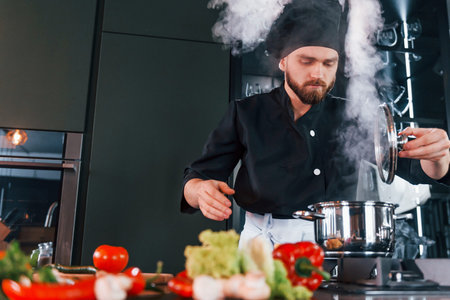 Preparing process. Professional young chef cook in uniform working on the kitchenの写真素材