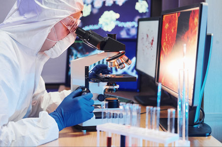 Scientist in white protective uniform near displays with data works with coronavirus and blood tubes in laboratoryの写真素材