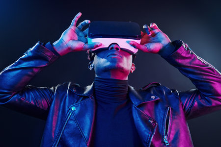 Virtual reality experience. Futuristic neon lighting. Young african american man in the studioの写真素材