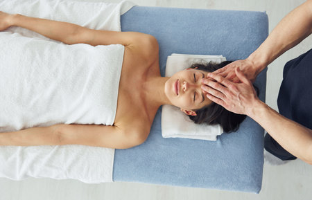 Top view. Young woman is lying down when man doing massage of her body at spaの写真素材