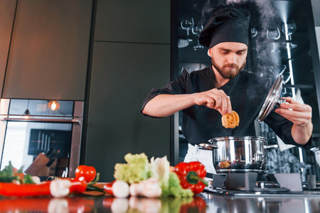 Preparing process. Professional young chef cook in uniform working on the kitchenの写真素材