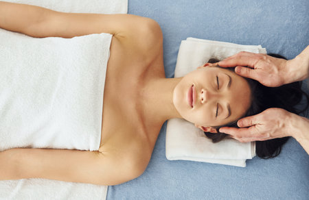 Top view. Young woman is lying down when man doing massage of her body at spaの写真素材
