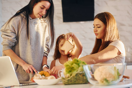 On the kitchen. Female lesbian couple with little daughter spending time together at homeの写真素材