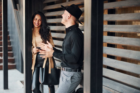 Woman with black curly hair and her man standing together near wooden windowsの写真素材
