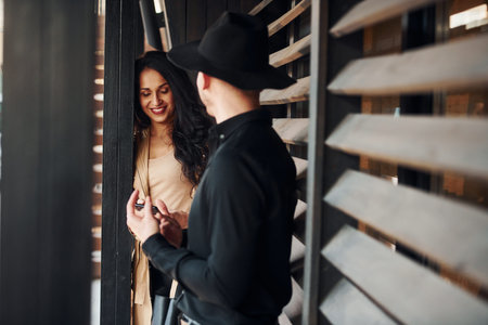 Woman with black curly hair and her man standing together near wooden windowsの写真素材