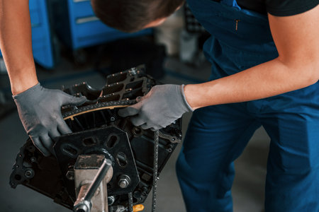 Close up view of professional repairman in garage that works with broken automobile engineの写真素材