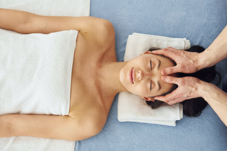 Top view. Young woman is lying down when man doing massage of her body at spaの写真素材