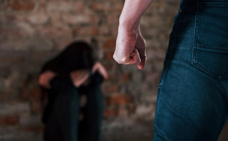 Violent man standing and threatens girl that sits on the floor with teddy bear in abandoned building