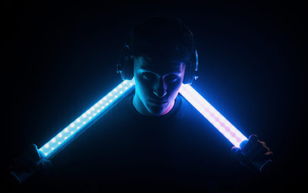 Guy uses headphones. Neon lighting. Young european man is in the dark studio
