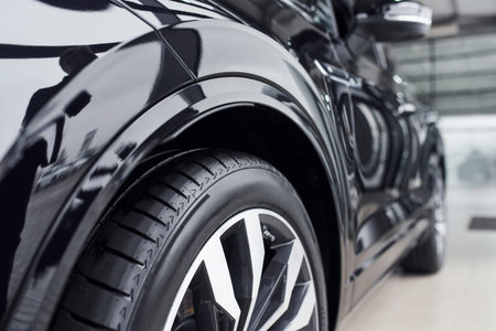 Particle close up view of modern new black automobile that parked indoors