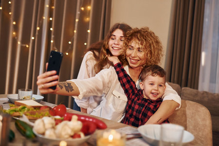 Happy family of mother, daughter and son is on the kitchen at evening timeの写真素材