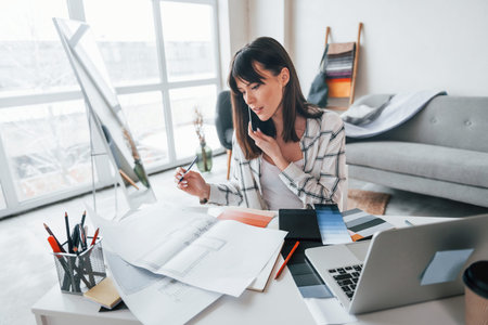 With laptop on the table. Young female freelance worker is indoors in home at daytime