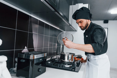 Professional young chef cook in uniform standing on the kitchenの写真素材