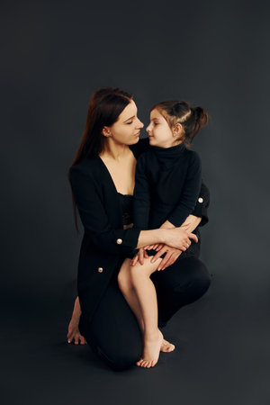 Mother and daughter is together in the studio against black backgroundの写真素材