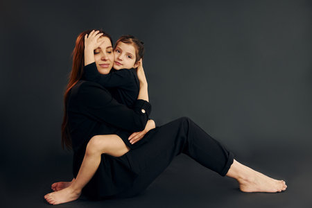 Mother and daughter is together in the studio against black backgroundの写真素材