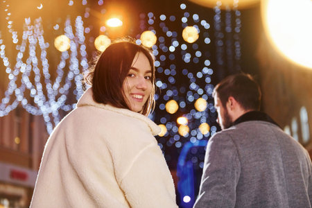 Beautiful garland lighting. Happy young couple celebrating New year outdoors on the streetの写真素材