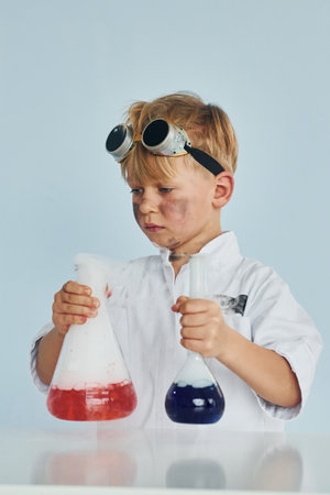 Little boy in coat playing a scientist in lab by using equipmentの写真素材