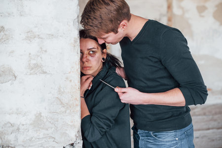 Kidnapped woman is threatened by man with knife in hands in abandoned building