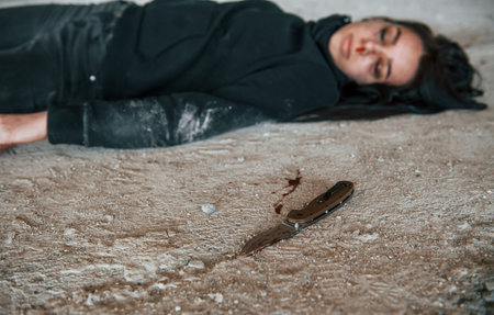 Corpse of female victim of crime lying down on the ground of abandoned buildingの写真素材