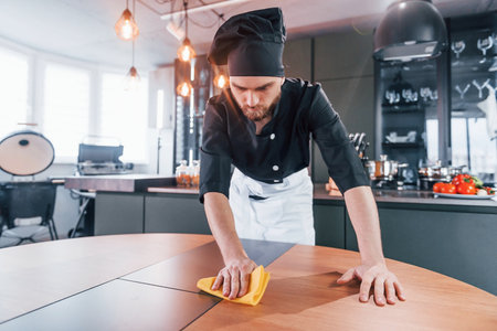 Professional young chef cook in uniform cleaning table on the kitchenの写真素材