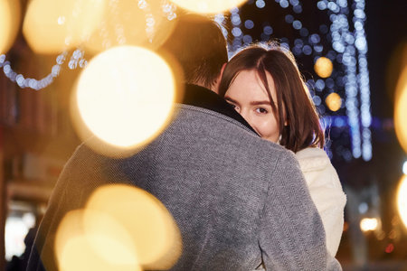 Beautiful garland lighting. Happy young couple celebrating New year outdoors on the streetの写真素材