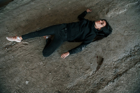 Corpse of female victim of crime lying down on the ground of abandoned buildingの写真素材