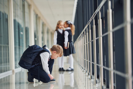 Boy sitting on the floor. School kids in uniform together in corridorの写真素材
