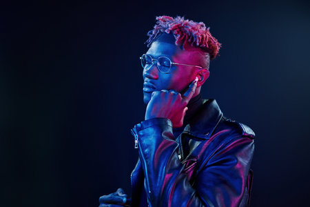 Listening to the music. Futuristic neon lighting. Young african american man in the studioの写真素材
