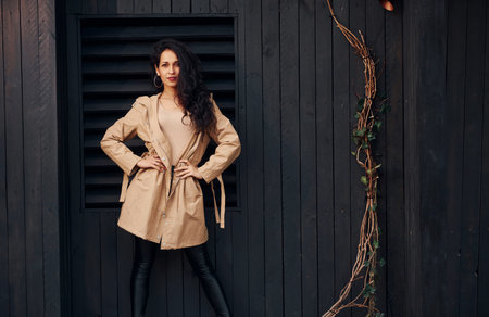 Woman with black curly hair standing against black wooden building exteriorの写真素材
