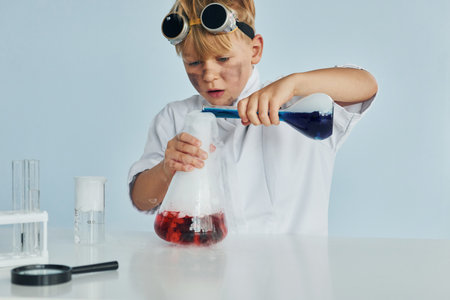 Little boy in coat playing a scientist in lab by using equipmentの写真素材