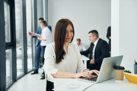 Woman in front of her colleagues. Group of people in official formal clothes that is indoors in the officeの写真素材