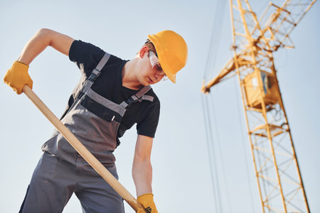 Using showel. Construction worker in uniform and safety equipment have job on buildingの写真素材