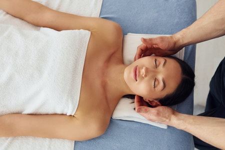 Top view. Young woman is lying down when man doing massage of her body at spaの写真素材