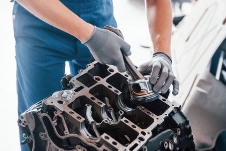Professional repairman works with broken automobile engine