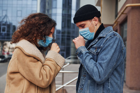 Couple in protective masks have a cough outdoors in the city near business building at quarantine time. Conception of coronavirusの写真素材