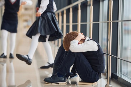 Boy in uniform sitting alone with feeling sad at school. Conception of harassmentの写真素材