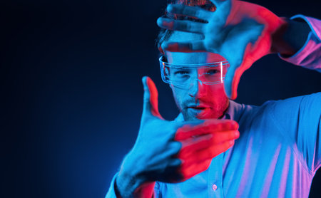 Virtual reality concept. Neon lighting. Young european man is in the dark studioの写真素材