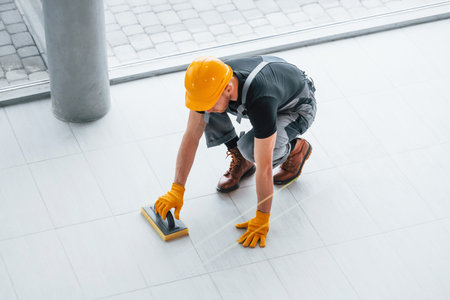 Top view of man in grey uniform that installing plate indoors in modern big office at daytimeの写真素材