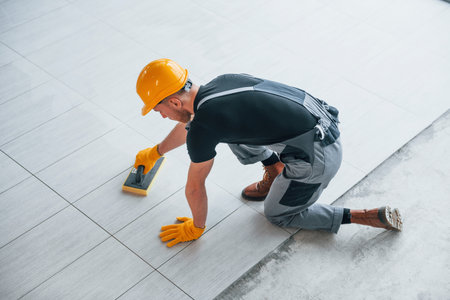 Top view of man in grey uniform that installing plate indoors in modern big office at daytimeの写真素材